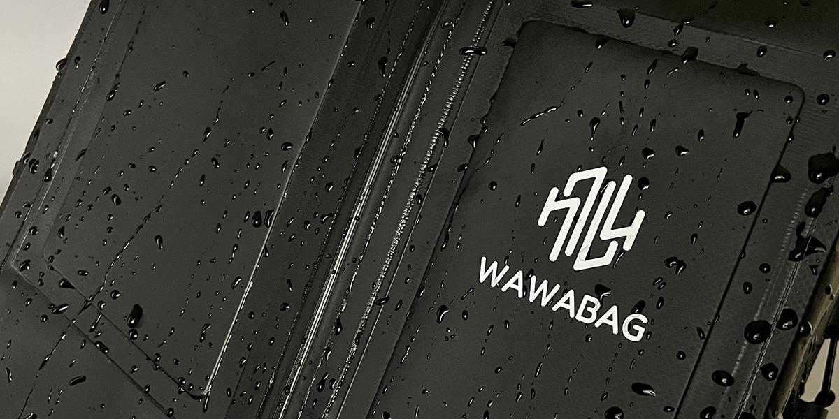 黑色 PVC Wawabag 的特寫，表面有雨滴，精美地突出了品牌標誌。.